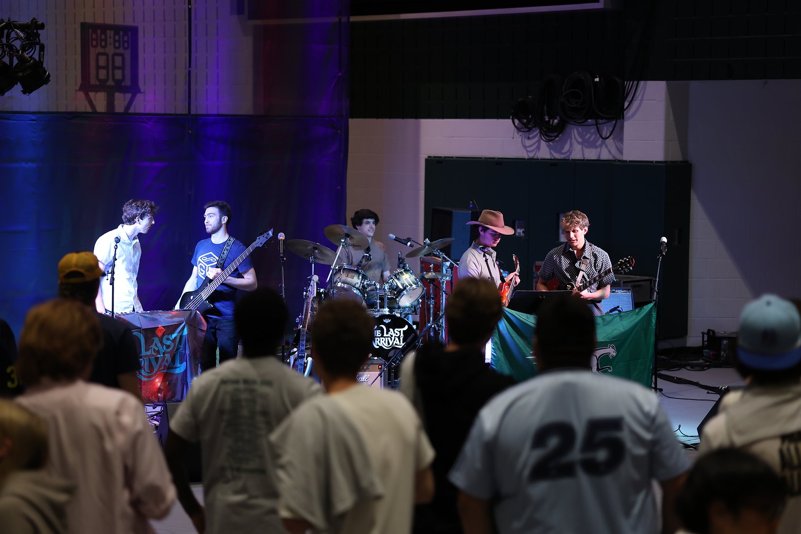 All five members on stage with the crowd watching from the floor