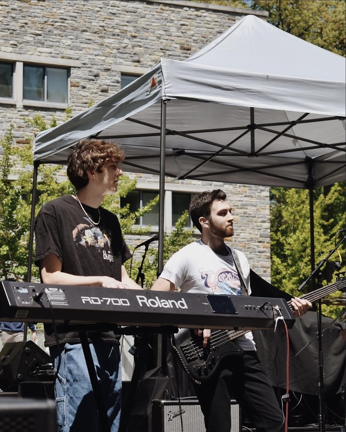 Keys player and bassist under a tent at an outdoor show