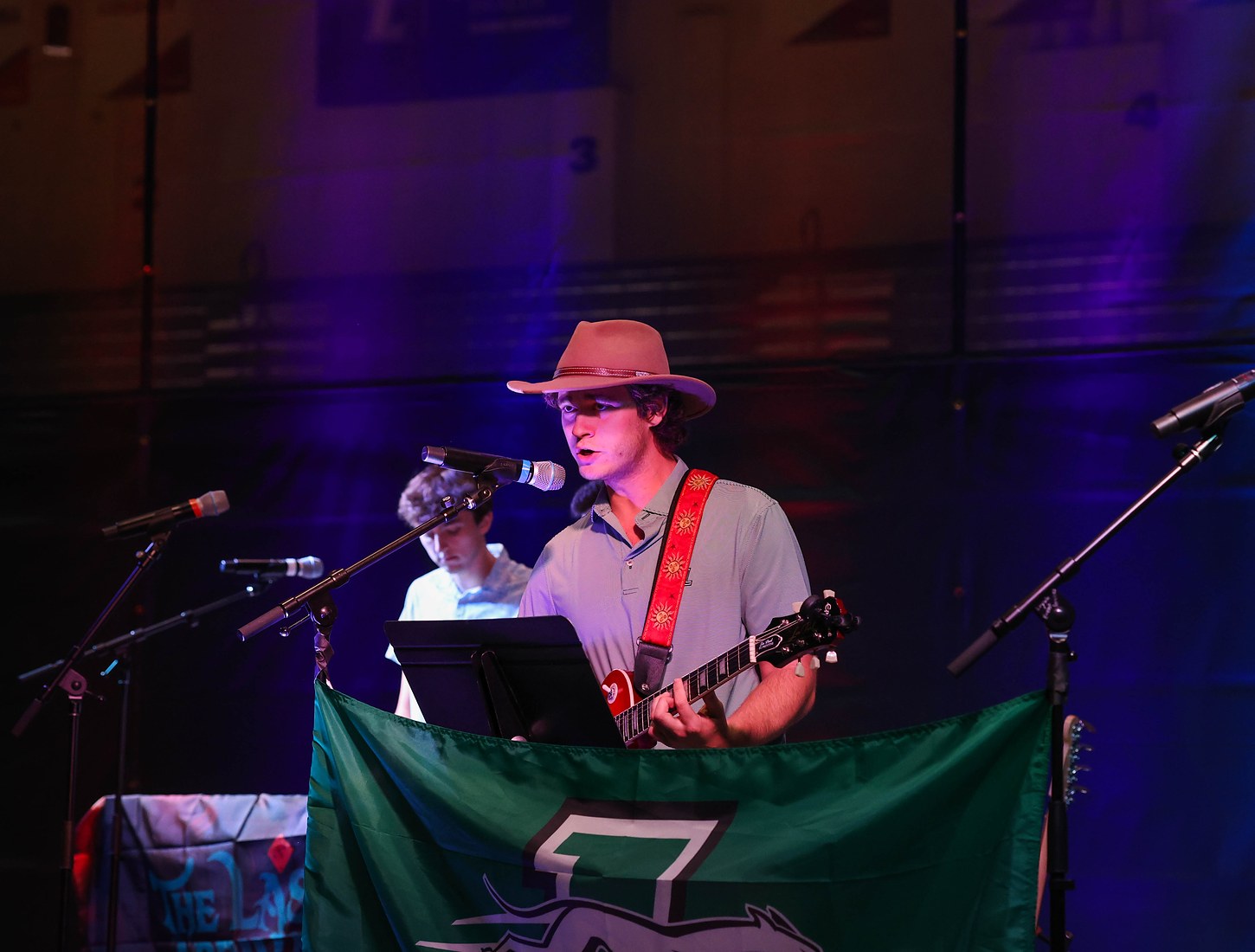 Singer and guitarist at the mic in front of the Loyola banner